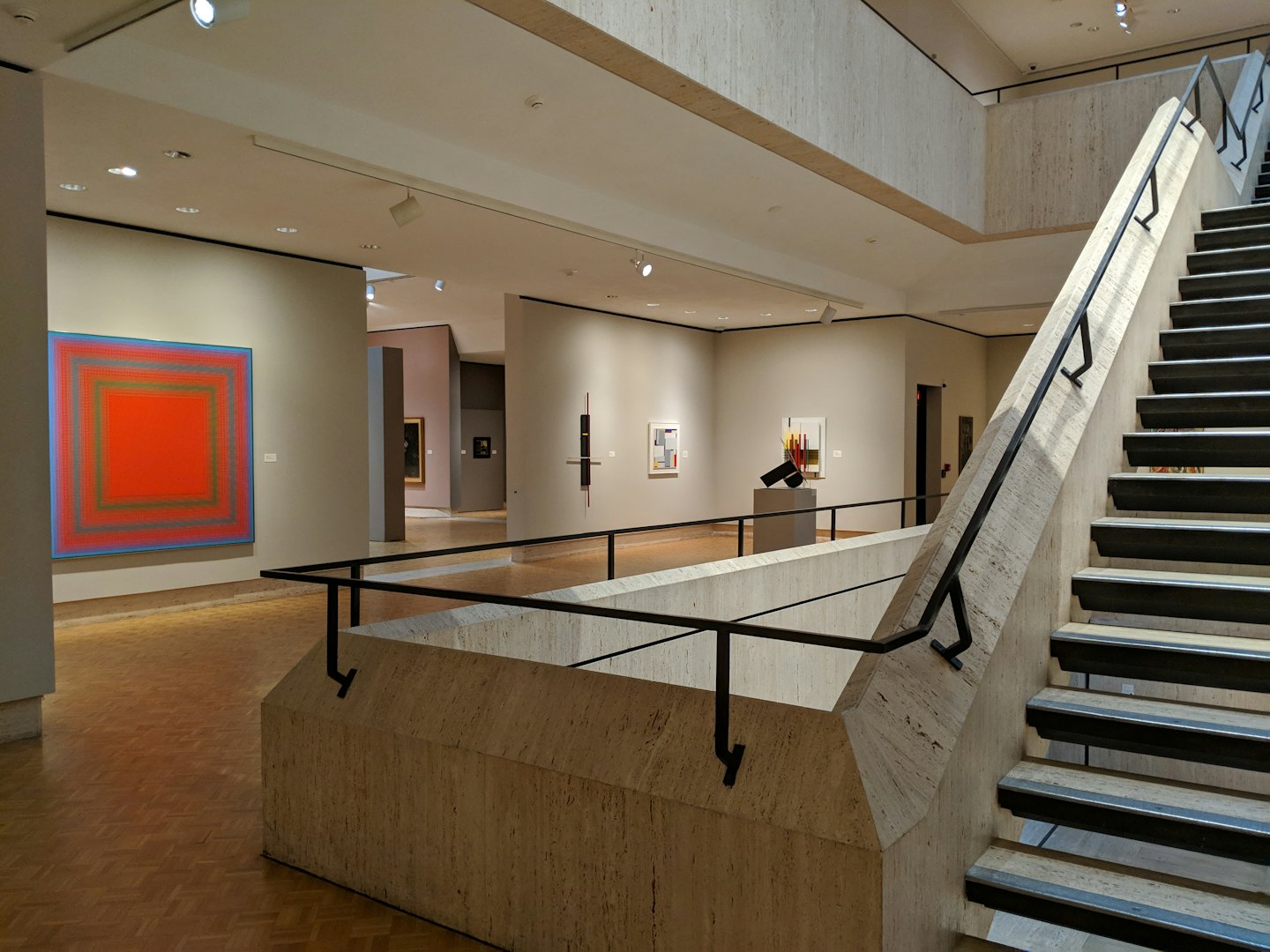 Modern art gallery with a large red painting and staircase.