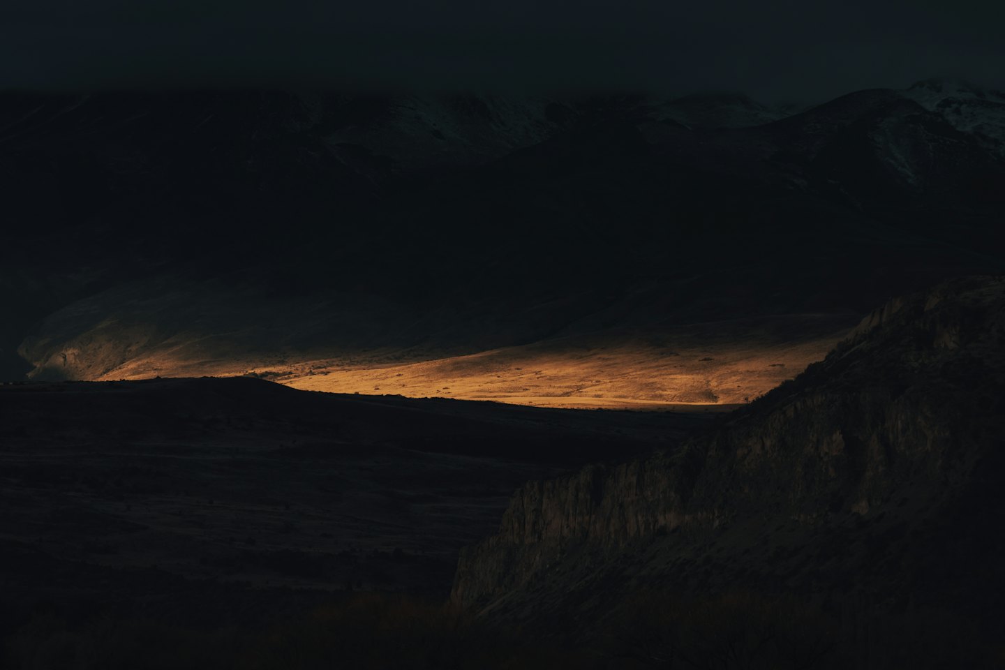 Sunlight illuminates a narrow section of the mountain range.