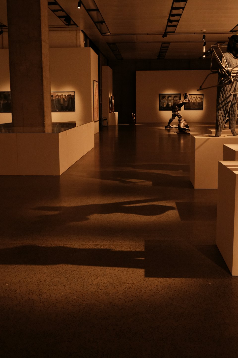 Art gallery hall displaying sculptures on white pedestals.